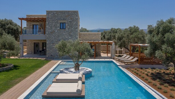 A modern villa with a stone facade, a swimming pool, and outdoor seating areas. - Thyme Villa (Rethymno)