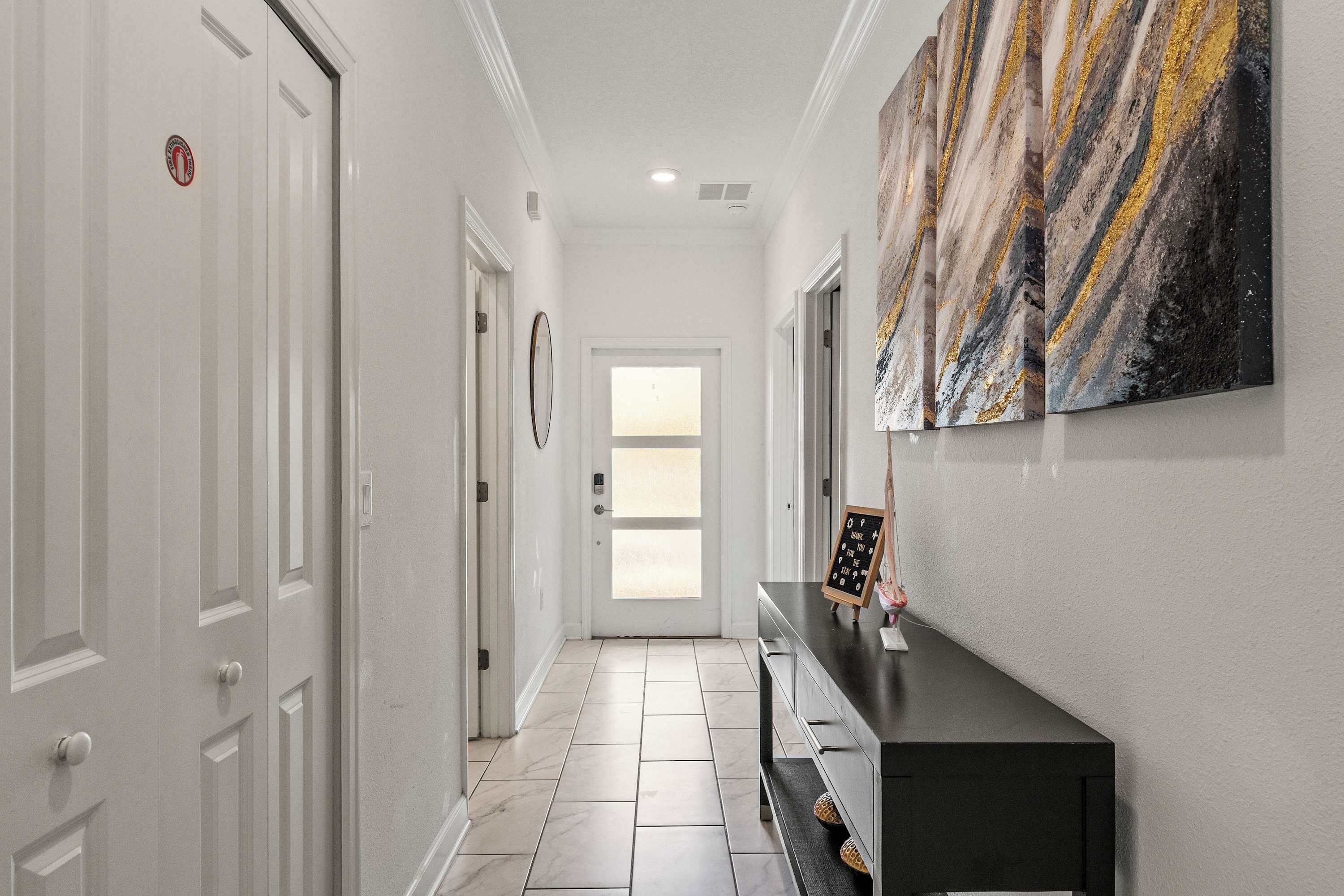 A hallway with white doors, a black console table, and a marble-patterned artwork on the wall.
