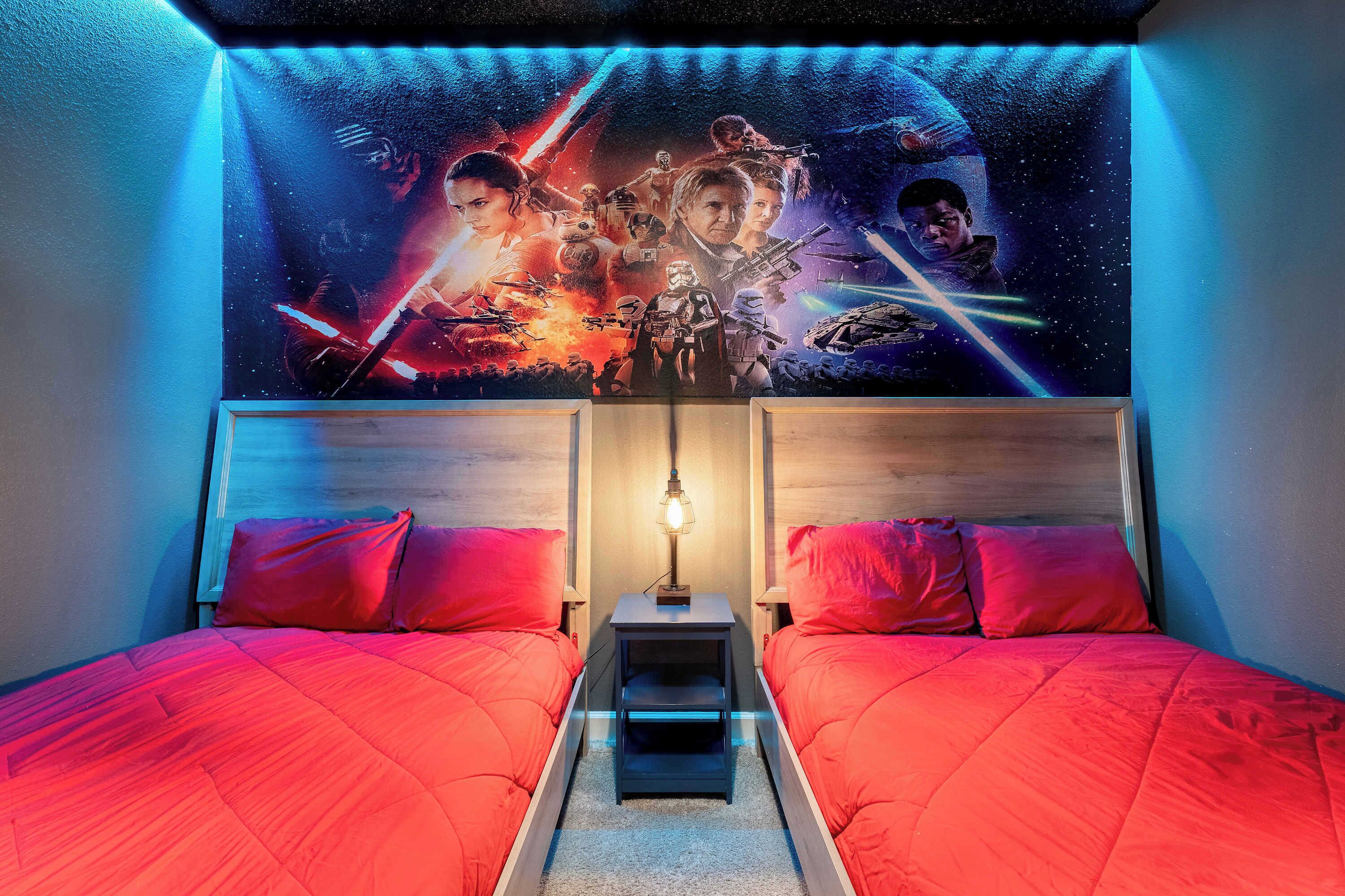 Et soveværelse med to senge, en væg med Star Wars-tema og et natbord med en lampe.