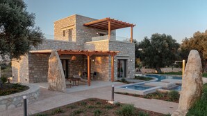 A modern house with a stone facade, a pool, and outdoor seating. - Rosemary Villa (Rethymno)