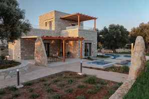 A modern house with a stone facade, a pool, and outdoor seating. - Rosemary Villa (Rethymno)
