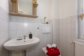 Une salle de bain avec un lavabo blanc, un miroir, un porte-serviettes et un radiateur.