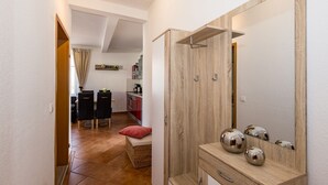 Un pasillo que lleva a una cocina con comedor, un espejo y un pequeño rincón de estar.