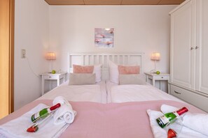 A double bed with white bedding, two nightstands with lamps, a painting on the wall, and a wardrobe. - Harmonie Vacation Rental - Harmonie Vacation Apartment in Rerik - Comfortable (Rerik)
