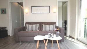 A modern living room with a grey sofa, two side tables, and a vase with flowers. - Linden Palais We 22 - Comfortable stay at the Linden Palais We 22 in (Bad Doberan)