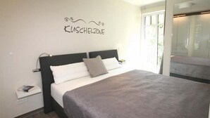 A modern bedroom with a bed, a nightstand, and a wall-mounted lamp. - Linden Palais We 22 - Comfortable stay at the Linden Palais We 22 in (Bad Doberan)