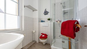 Une salle de bain moderne avec une grande baignoire, une douche à l’italienne et des toilettes.