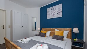 Une chambre d’hôtel comprenant un lit, deux tables de chevet, une commode, un miroir et une œuvre d’art murale.
