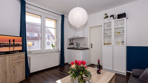 Un salon moderne avec une table basse en bois, un téléviseur, un coin repas et une cuisine.