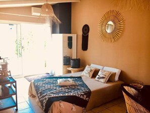 Une chambre à coucher comprenant un lit, une table de chevet, une chaise, une horloge murale et un miroir décoratif.