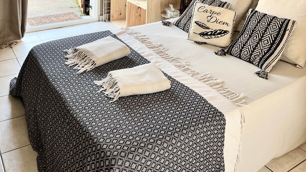 Ein Schlafzimmer mit Bett, Kleiderschrank, Pendelleuchte und Wandbild.