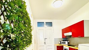 A kitchen with white cabinets, a red countertop, and a microwave. - Cozy 1BR and Living Room Apartment (Vienna)
