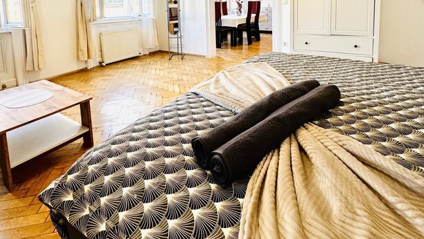A hotel room with a large bed, a wooden floor, a desk, and a wardrobe. - Cozy 1BR and Living Room Apartment (Vienna)