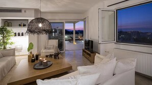 Un soggiorno moderno con divano, tavolino e televisione. Una grande finestra offre vista sulla città.