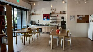 A modern kitchen with a central island, wooden chairs, and a dining table. - Popinn International Youth Hostel (Tainan)
