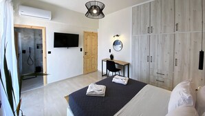 Een moderne slaapkamer met een bed, een bureau, een kledingkast, een televisie en een airconditioning.