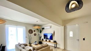 Een moderne woonkamer met een bank, televisie en decoratieve planten.