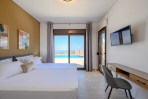 Ein Hotelzimmer mit einem großen Bett, einem Schreibtisch, einem Fernseher und Meerblick.