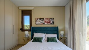 Un dormitorio con una cama, dos mesitas de noche, una ventana y una puerta.