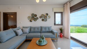 Una sala de estar moderna con un sofá modular, una mesa de centro de madera, decoración en la pared y un ventanal con vistas.