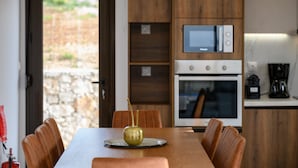 Un comedor con una mesa, sillas, un jarrón decorativo, un microondas, un horno y una cafetera.