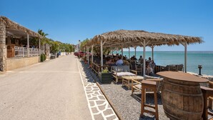 A seaside restaurant with outdoor seating, a stone pathway, and a view of the sea. - Vigla Villa (Viannos)