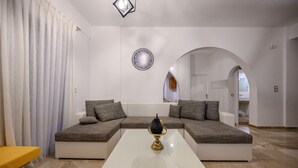A modern living room with a sectional sofa, a white coffee table, and a wall clock. - Vigla Villa (Viannos)