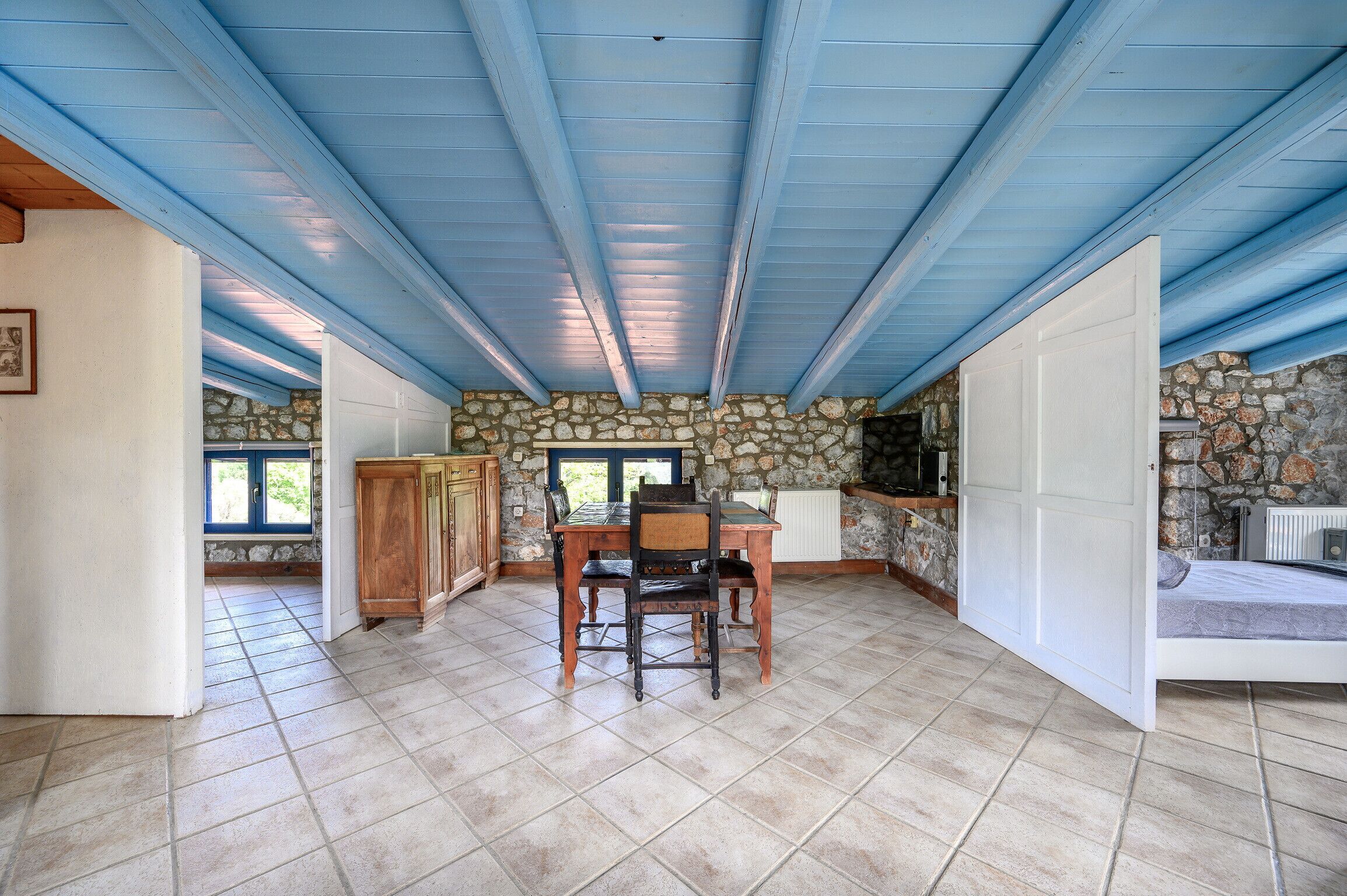 A spacious dining area with a stone wall, a wooden table, and chairs.