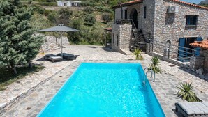 Un bâtiment en pierre doté d’une piscine, d’un espace extérieur aménagé et d’un escalier menant à un niveau supérieur.
