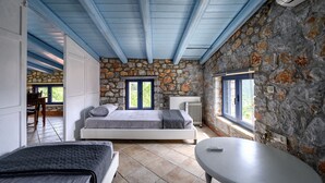 Une chambre avec un mur en pierre, un lit, une table et une fenêtre.