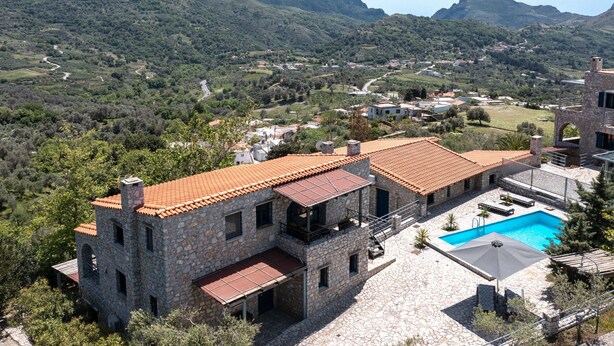Un bâtiment en pierre doté d’une piscine, entouré d’un paysage montagneux et de verdure.