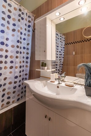Ein modernes Badezimmer mit einem weißen Waschbecken, einem Spiegel und einer Duschvorhang mit Punkten.