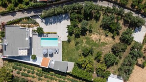 Vista aérea de una propiedad con piscina, zona de estar exterior y jardín ajardinado.