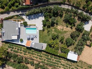 An aerial view of a property with a swimming pool, outdoor seating area, and a landscaped garden. - Angeliana Villa (Mylopotamos)