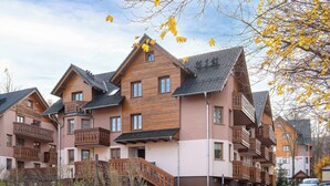 Ein mehrstöckiges Wohngebäude mit Balkonen, einer Holzfassade und einem überdachten Eingang.