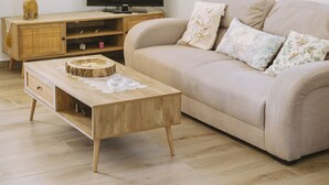 A living room with a beige sofa, a wooden coffee table, and a television on a wooden stand. - Villa Panormo Crete (Mylopotamos)