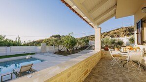 A pool area with a pergola, outdoor seating, and a view of a hillside. - Villa Panormo Crete (Mylopotamos)