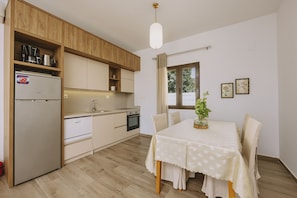 Eine kompakte K üche mit Holzschränken, einem Einbauofen und einem Essbereich mit Tisch und Stühlen.
