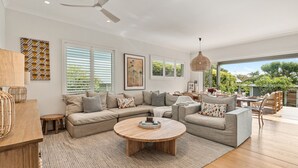A modern living room with a sectional sofa, a round coffee table, and a dining area with a table and chairs. - Tranquil & Spacious Parkside Retreat in Willoughby (Willoughby East)