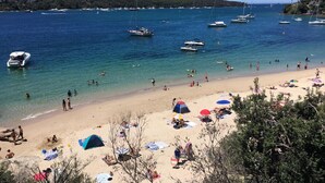 A beach with clear blue water, boats, and people enjoying the shore. - Tranquil & Spacious Parkside Retreat in Willoughby (Willoughby East)
