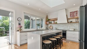 A modern kitchen with a large island, bar stools, and a view of the outdoors. - Tranquil & Spacious Parkside Retreat in Willoughby (Willoughby East)