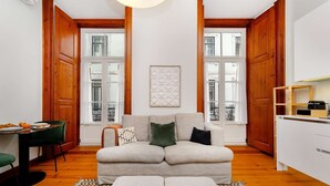 A cozy living room with a sofa, ottoman, and a dining area with a table and chairs. - Modern Comfort in Old Lisbon (Lisbon)