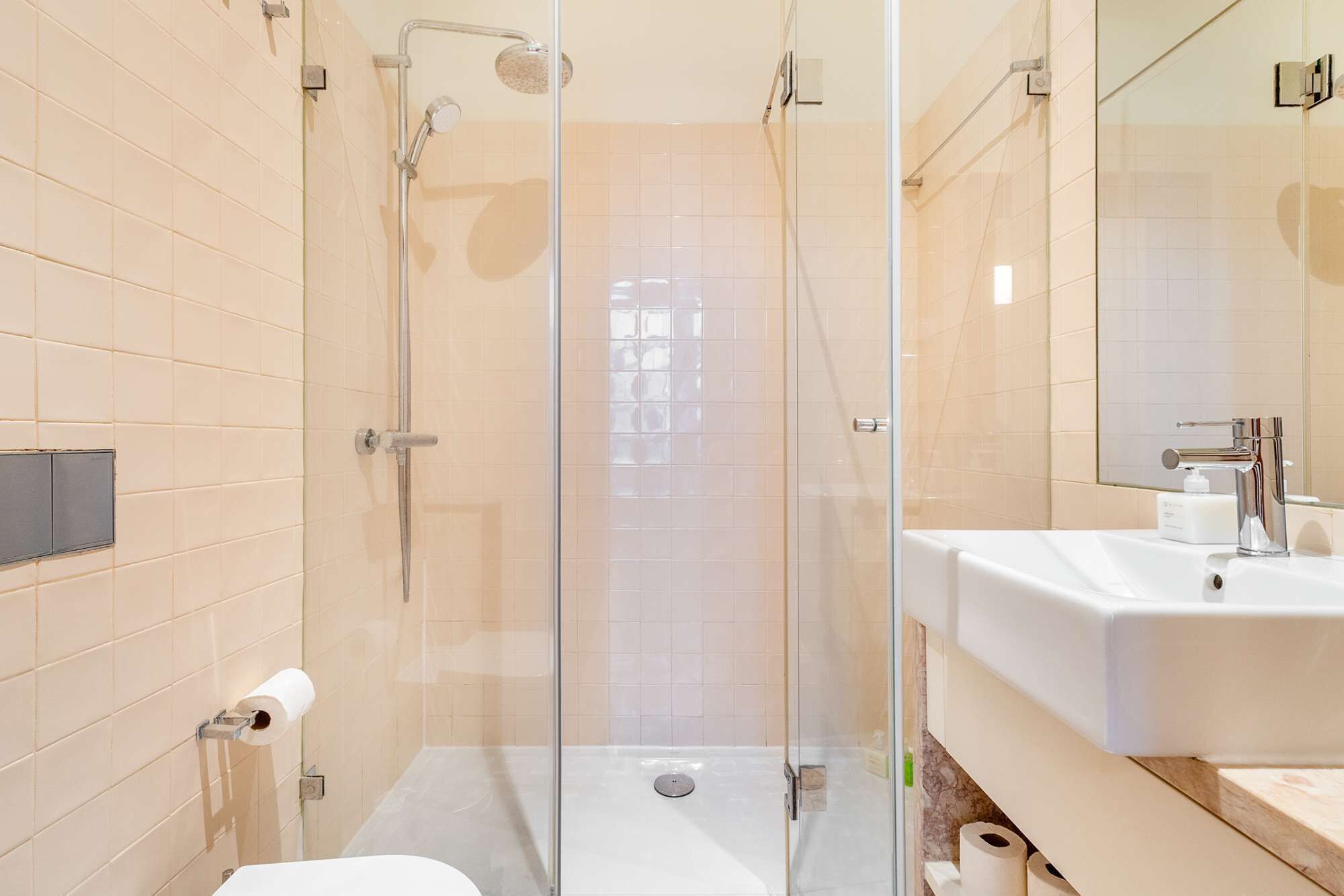 A modern bathroom with a glass-enclosed shower, a white sink, and a toilet.