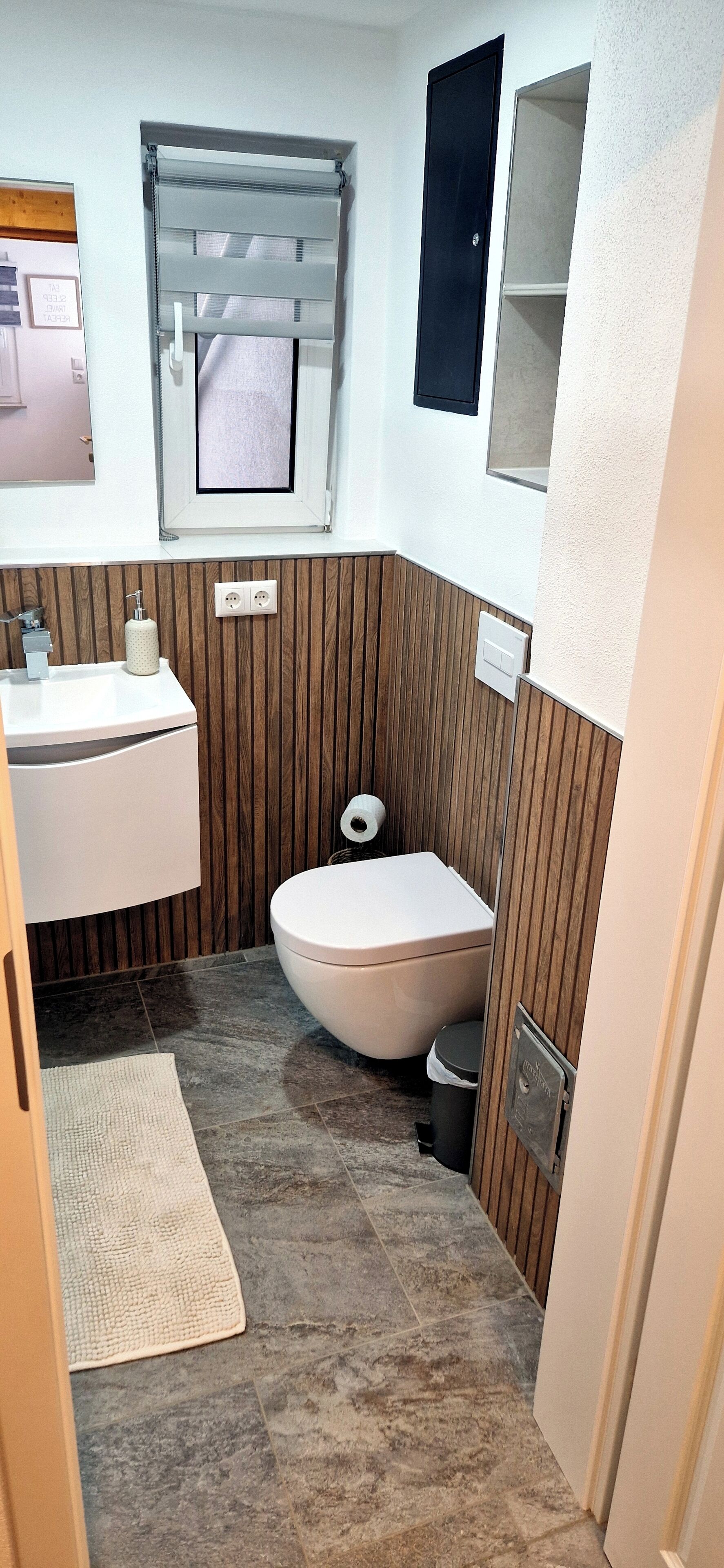 Une petite salle de bain avec des toilettes, un lavabo et une fenêtre.