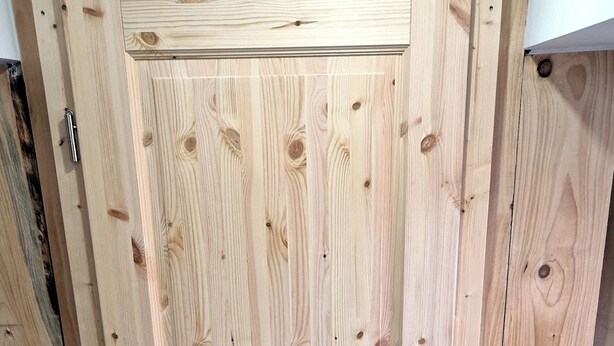 Una puerta de madera con picaporte y un pequeño ventanal.