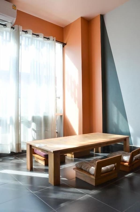 Ein modernes Wohnzimmer mit einem Holztisch und zwei Sofas, einem großen Fenster mit Vorhängen sowie einem einzigartigen Wanddesign.