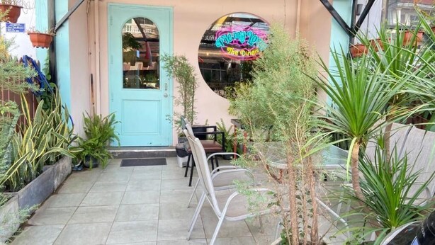 A restaurant with a turquoise door, outdoor seating, and potted plants. - Pie My Love (Vientiane)