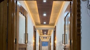 Corredor com portas de madeira, piso ladrilhado e iluminação embutida.