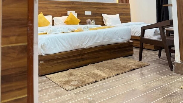 Quarto moderno com cabeceira de madeira, parede decorativa em mármore e piso de madeira.