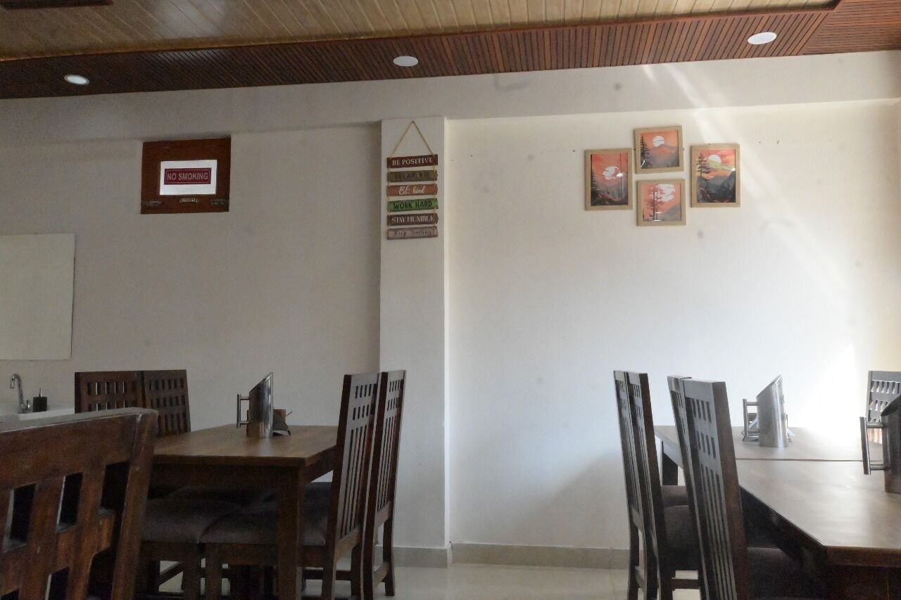 A dining area with wooden tables and chairs, a 'No Smoking' sign, motivational signs, and framed artwork on the wall.